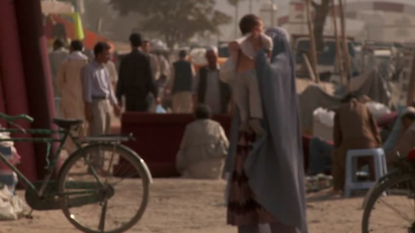 KABUL, AFGHANISTAN - CIRCA 2009: Slow-motion shot of a woman in burka walking with her child circa 2009 in Kabul, Afghanistan. The official religion in Afghanistan is Islam, which is practiced by over 99% of its citizens. 