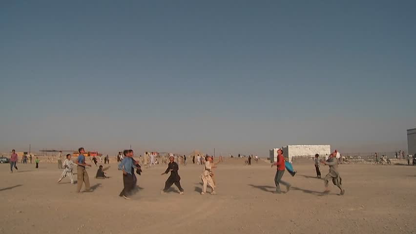 KABUL, AFGHANISTAN - CIRCA 2009: Kids chase and play with kites in an empty lot circa 2009 in Kabul, Afghanistan. Afghanistan is an impoverished and least developed country, one of the world's poorest.  