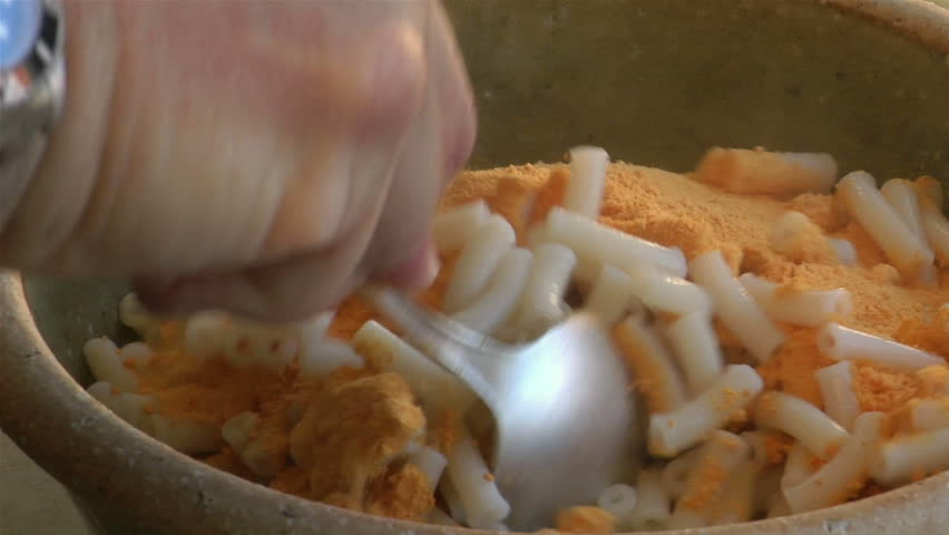 Macaroni is stirred in a bowl.