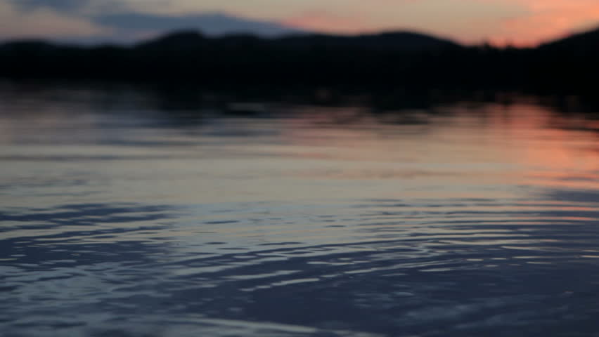 shallow focus on the foreground of calm lake water at dusk on Lows lake, Adirondack state park,New York, USA.
