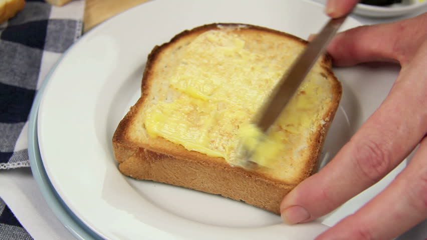 Butter being spread on a hot toast slice. 