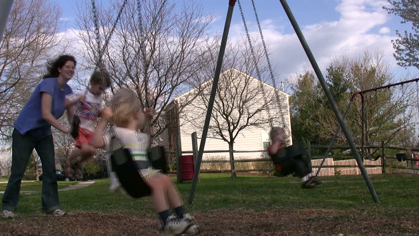 children enjoy a beautiful spring day swinging at the playground