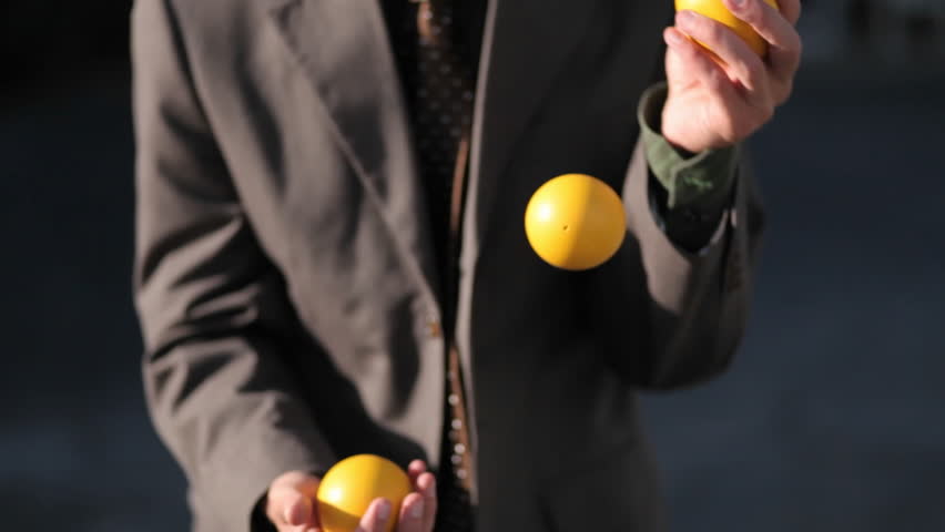 The man effortlessly juggles three balls.