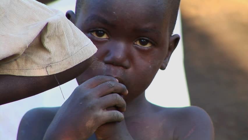 UGANDA, AFRICA - CIRCA 2009: A young orphan child touches his fingers to his mouth in a camp circa 2009 in Uganda.