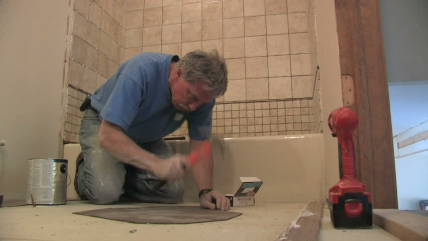 Man fixes bathroom floor.