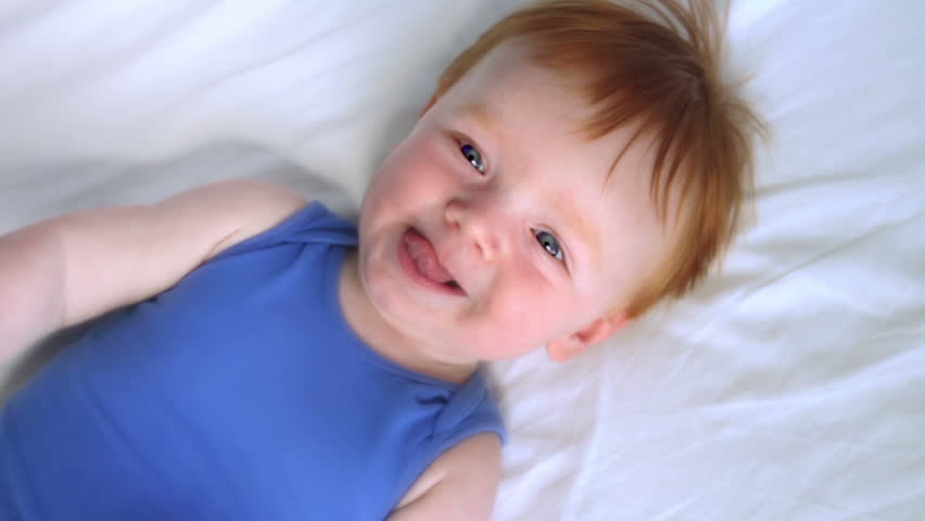 HD: Laughing baby medium Two shot of a happy baby smiling at camera. The little red hair baby boy swings his arms while laughing at camera.