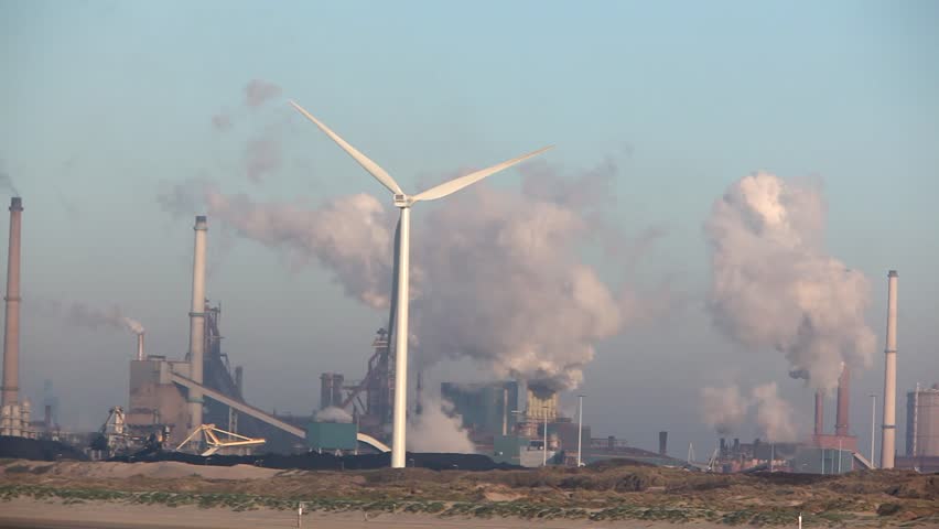 Wind turbine with big smokestacks in the background