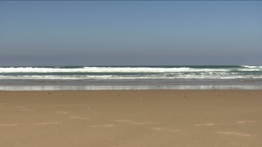 Surfer walking with his surfboard along the beach