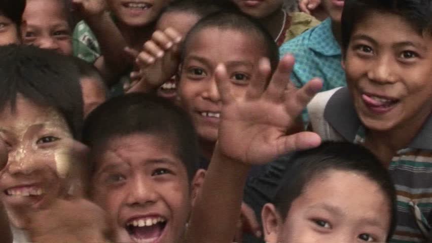 MYANMAR - CIRCA 2009: A crowd of children smile and wave at the camera in Myanmar circa 2009