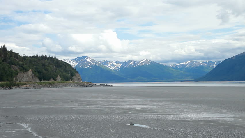Cook Inlet at low tide, outside of Anchorage Alaska. Named at famous Captain Cook who explored the region. Traffic on highway on the way south to Kenai Peninsula.