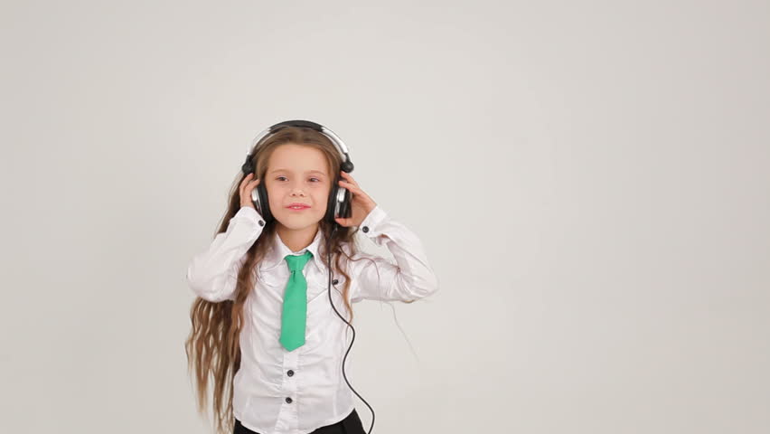 Girl with headphones. The little girl with long hair dancing with headphones on a white background.