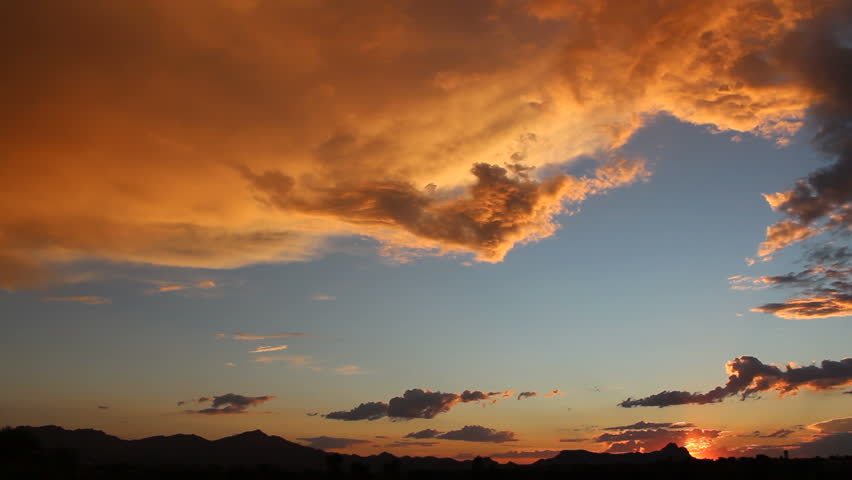 Pan across beautiful, red hued clouds in blue sky at sunset. 1080p