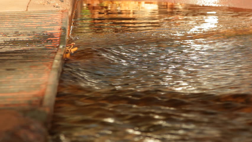 The waters of Oak Creek in Sedona rush quickly into a storm grate as the beautiful fall colors are reflected in the ripples.