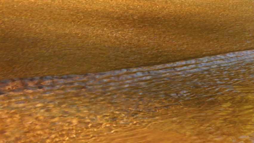 Closeup of waters of Oak Creek in Sedona, Arizona ripple rapidly over a concrete area as the fall colors are reflected.