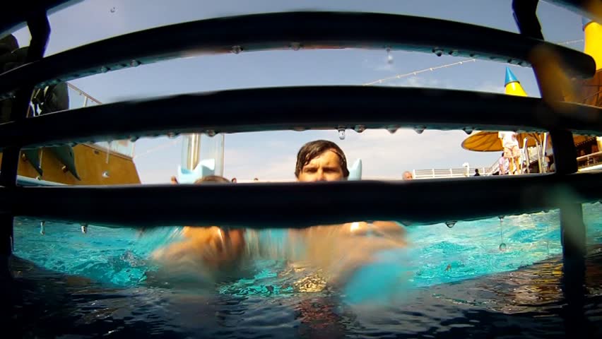 Son with father jump in pool, view through lattice