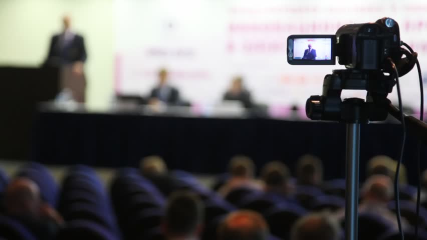 videocamera keeps record of performance of lecturer in presentation hall