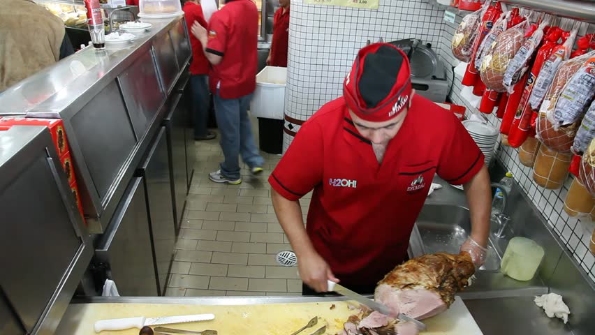 SAN PAULO, BRAZIL - CIRCA JUNE 2011: A cook slices cured ham in a restaurant kitchen circa June 2011 in San Paulo.
