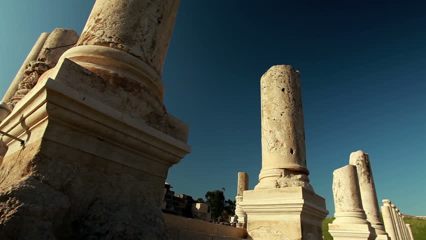 Slider dolly move right to left and up the base of a column at the ruins in Beit She'an, Israel.  Other columns, some more ornate, can be seen in the shot continuing down the ancient Palladius street.