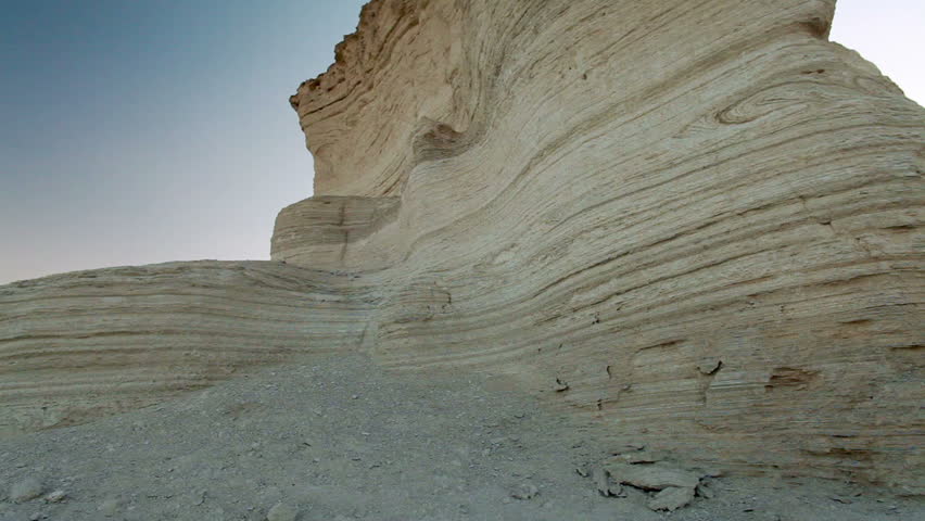 Slider dolly move left to right with a low angle looking up at the texture and layers of a desert rock formation at Ein Gedi Israel.