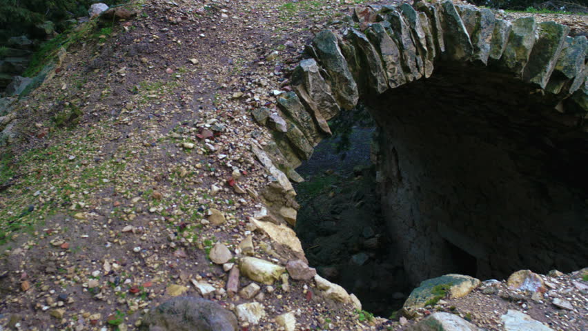 A pan left to right of an archway looking down to an under ground area with an entry way and a very small window, in the ancient ruins of Bar'am, Israel. 02/20/2011