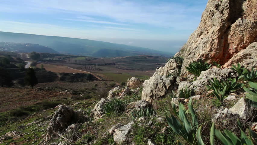 Slider dolly shot down-left to up-right of the fields and orchards along the hillsides and valley of the Golan Heights in Israel.  