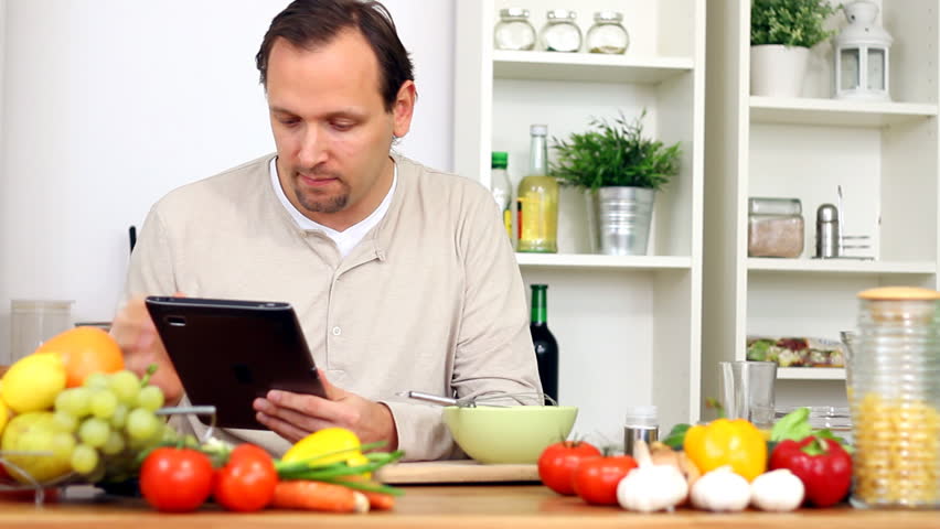 Man cooking and looking at recipe on digital tablet 