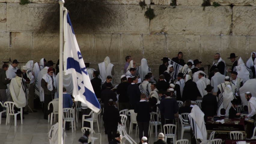 ISRAEL - FEB 2011: Israeli flag in the foreground and male Jews at the Western Wall (Wailing Wall)