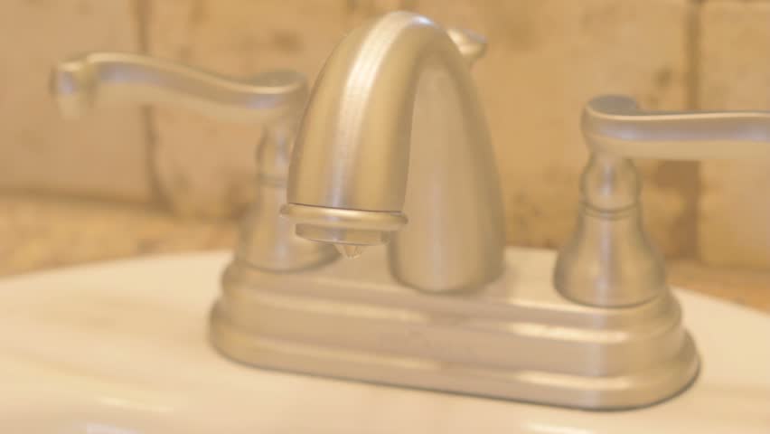 Stainless steel water faucet in bathroom dripping water