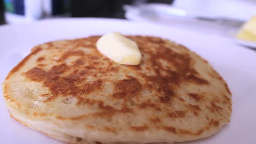 Maple syrup is poured over delicious pancake