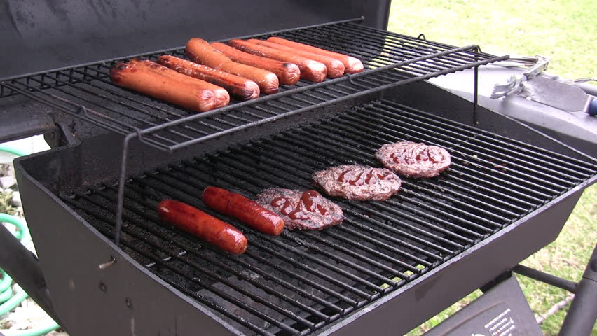 Hot dogs being turned on grill.