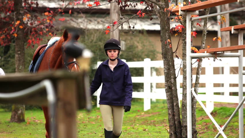 Young girl leads her horse to the arena.