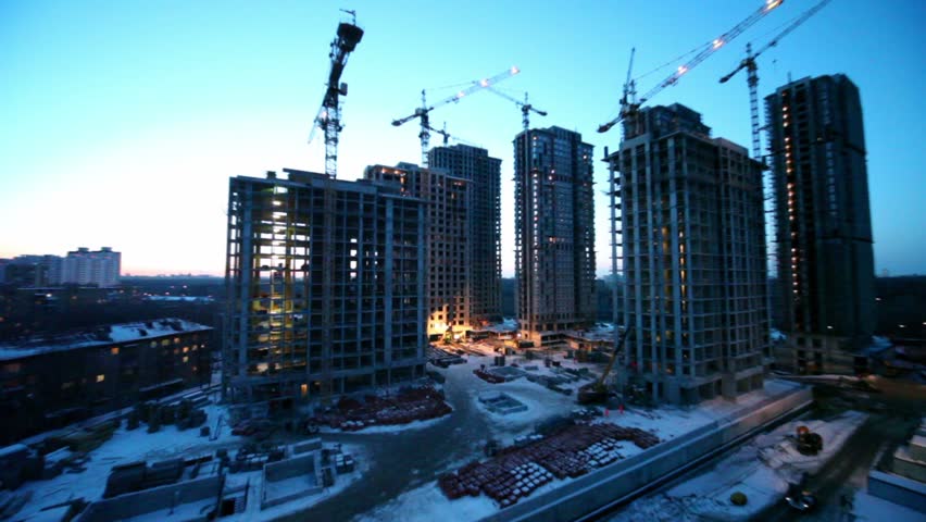 Labourers at construction site dormitory area at background on winter evening, camera zoom in