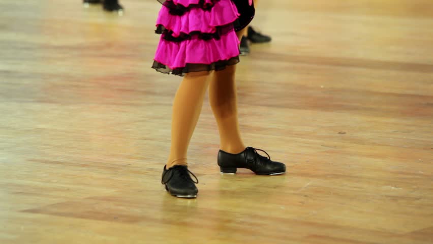Girl in shoes with taps and pink skirt tap dance, only legs are visible