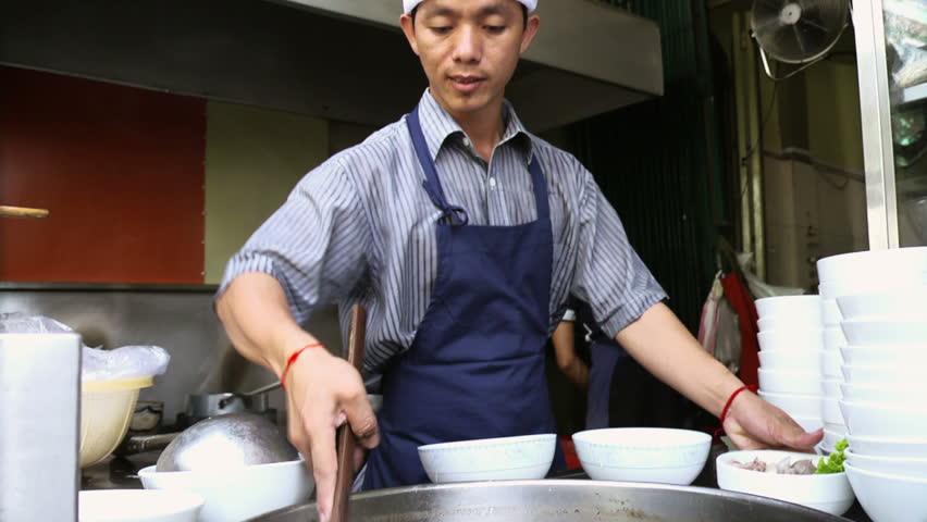 Chef preparing traditional Asian street food and working in restaurant kitchen, Phnom Penh, Cambodia, Asia. Low angle