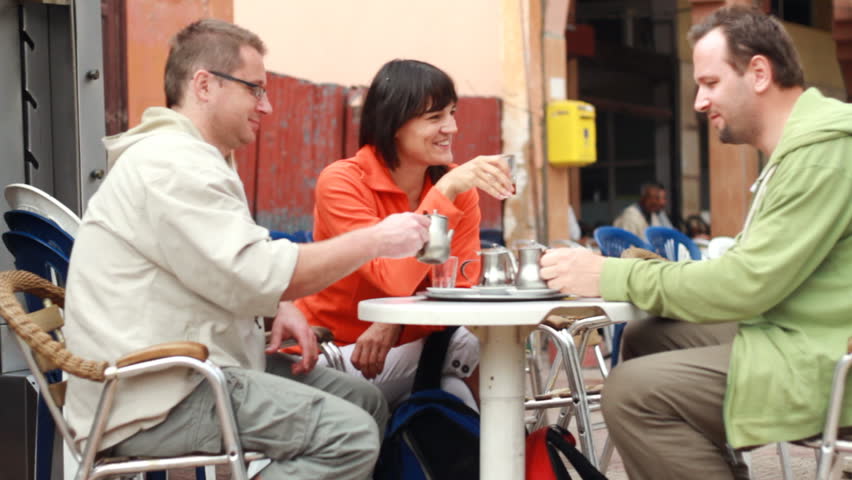 Young friends talking and drinking tea in bar, outdoors