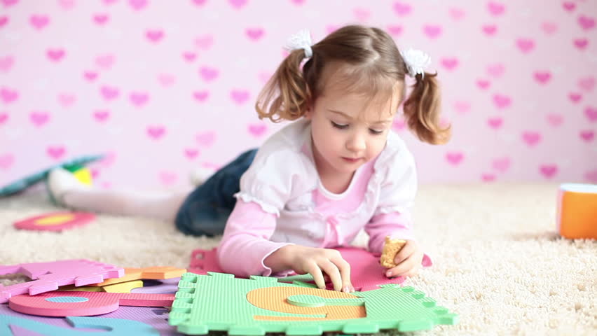 Girl lying on the floor playing and eating biscuits