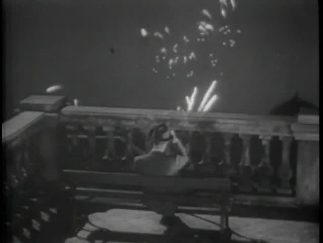 Rear view of man on bench watching fireworks from terrace