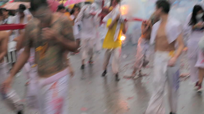 PHUKET, THAILAND - OCT 3: Volunteers in vegetarian procession walk through firecrackers exploding from people who join in the festival on October 3, 2011 in Phuket Thailand.