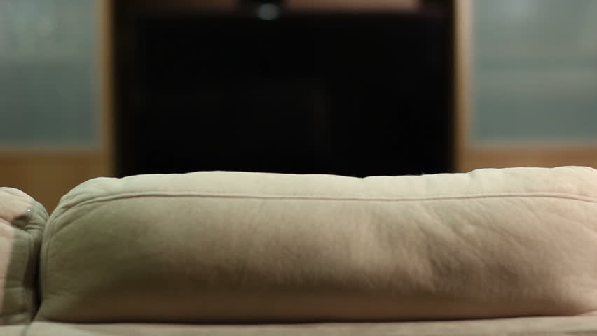 HD clip of a balding man sitting down on a couch and watching TV, while channel surfing