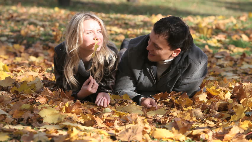 Couple spending time together lying on maple leaves in park