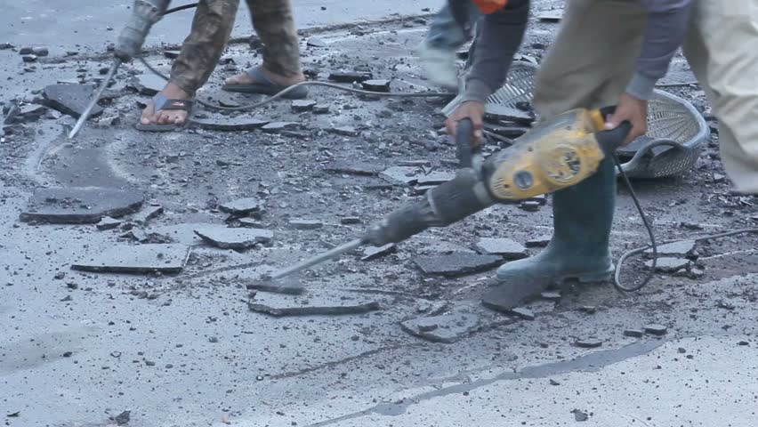 The man using Jack hammer breaking road surface.