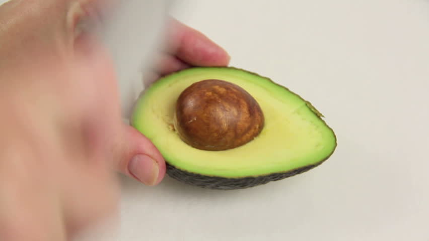 Close up of taking a seed out of an avocado then slicing for serving. 