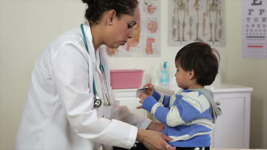A pretty Hispanic pediatrician patiently examines a playful toddler.