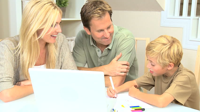 Proud parents watching son using laptop and crayons