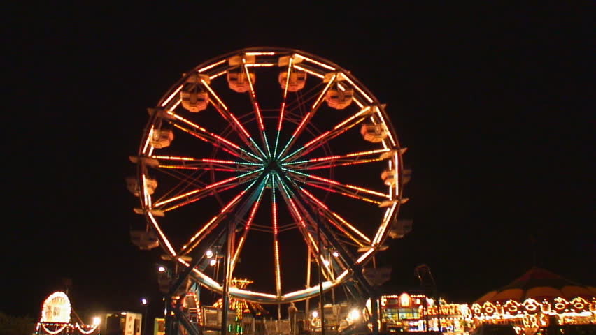 Ferris wheel lights sparkle brightly as it slows to add passengers