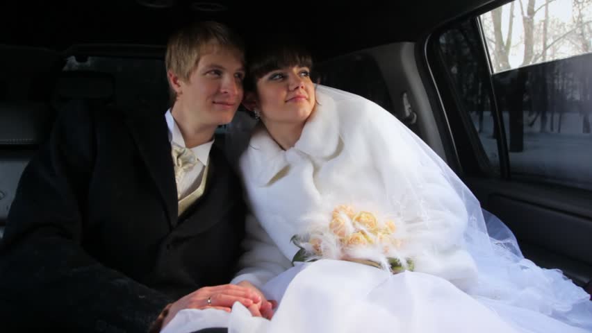 Newly-married couple sits in limousine having nestled to each other and it irons it on hand