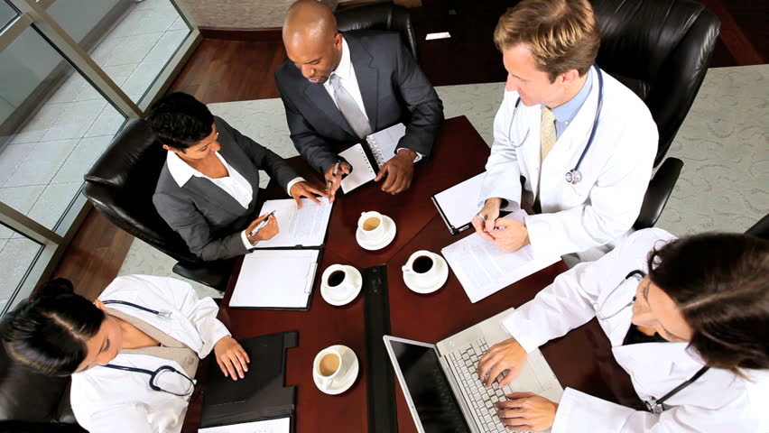 Overhead shot of multi ethnic medical executives and financial advisors meeting in a modern hospital boardroom