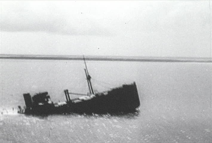 ATLANTIC OCEAN - CIRCA 1942-1944: World War II, Fly by Of Sinking Freight Ship, publisher National Broadcasting Service (U.S.) 