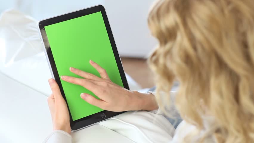 Back view of woman at home using electronic tablet