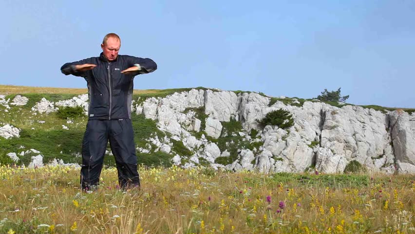 The man in a jumpsuit is kneaded on a grass in mountains